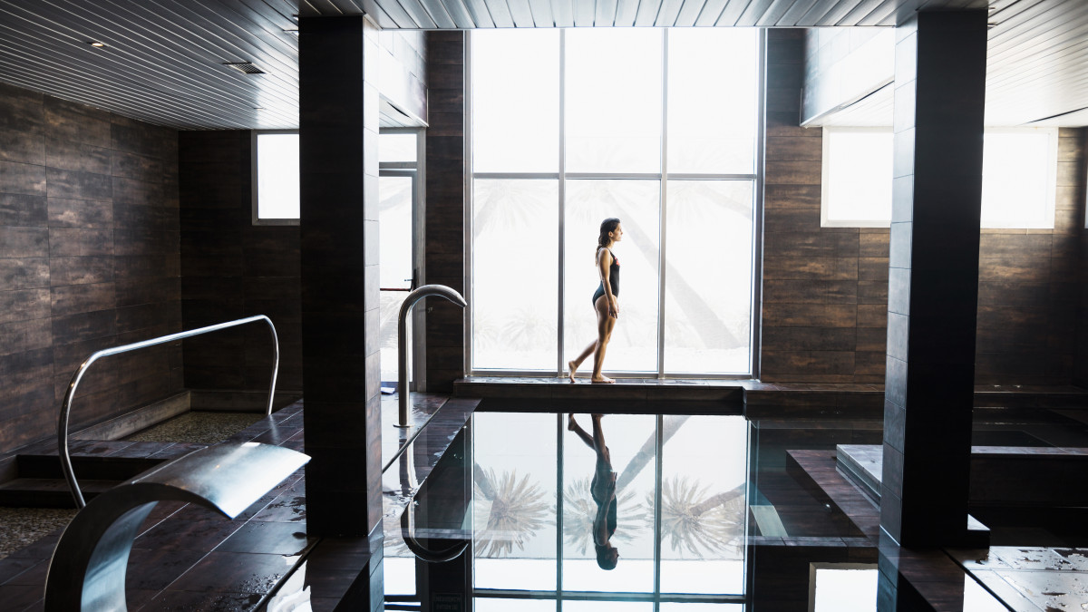une femme déambule le long d'une piscine dans un hotel